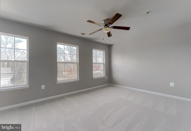 unfurnished room featuring visible vents, light colored carpet, baseboards, and ceiling fan