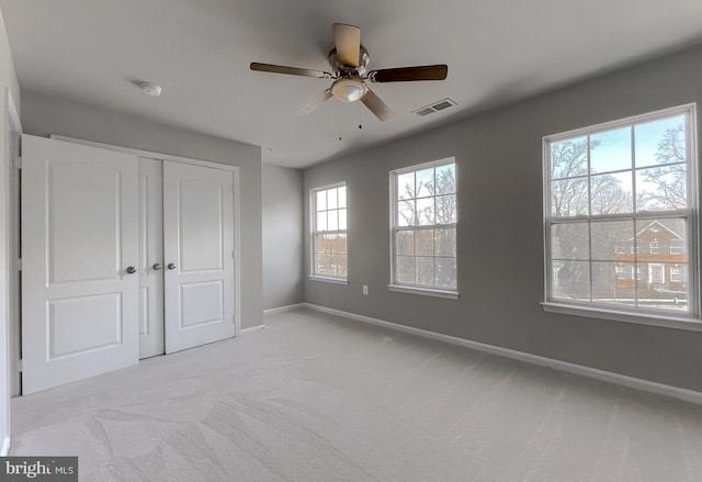 unfurnished bedroom featuring a closet, visible vents, light colored carpet, and baseboards