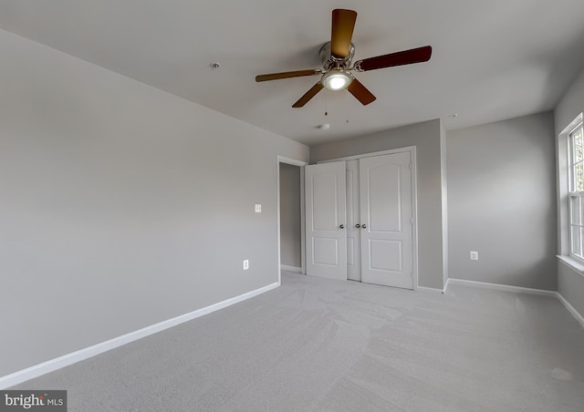 unfurnished bedroom featuring a closet, baseboards, light carpet, and a ceiling fan