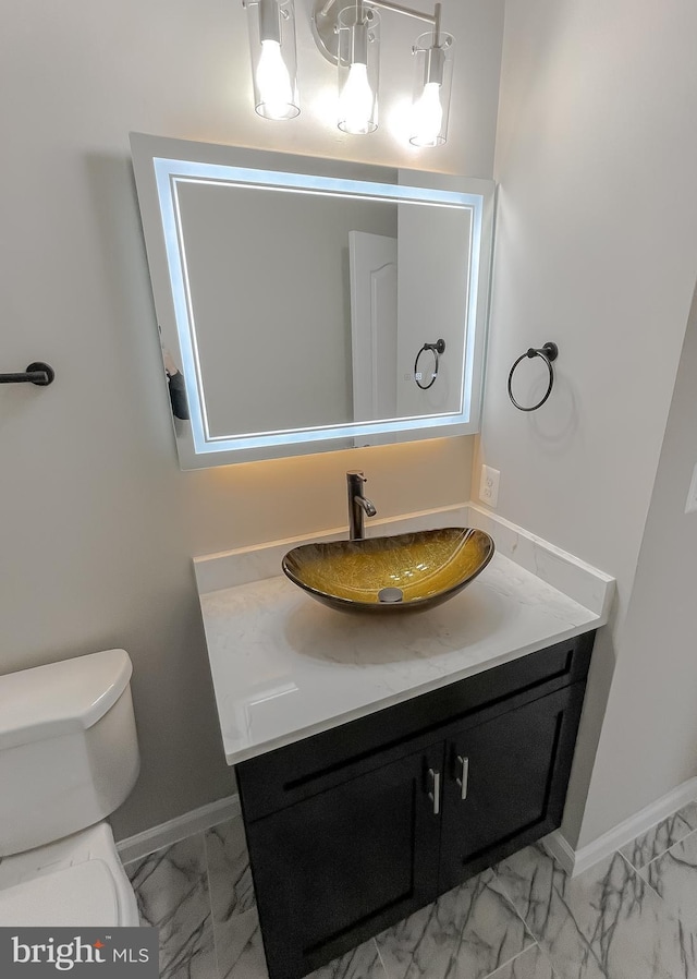 bathroom with baseboards, marble finish floor, vanity, and toilet