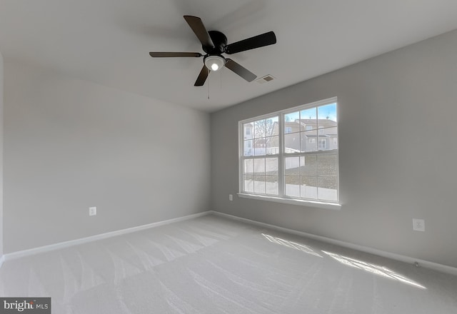 spare room with a ceiling fan, visible vents, light colored carpet, and baseboards