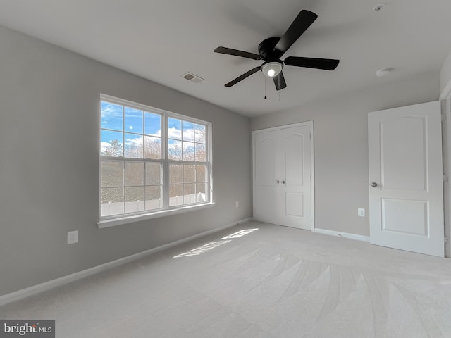 unfurnished bedroom featuring light colored carpet, baseboards, visible vents, and a ceiling fan