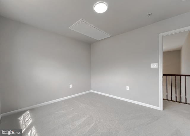 empty room with attic access, carpet, and baseboards