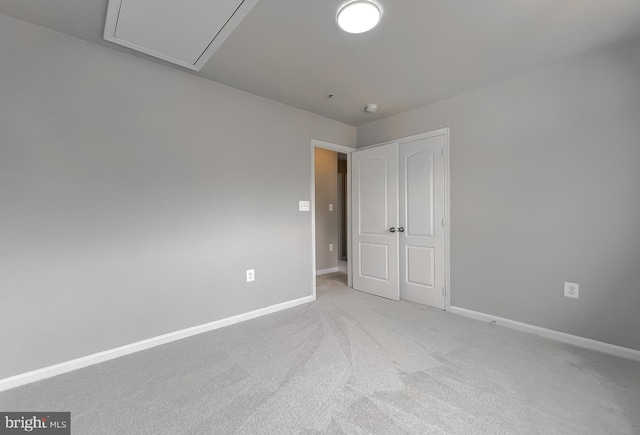 carpeted empty room with baseboards and attic access