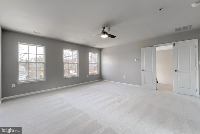 unfurnished bedroom featuring visible vents, light colored carpet, baseboards, and ceiling fan