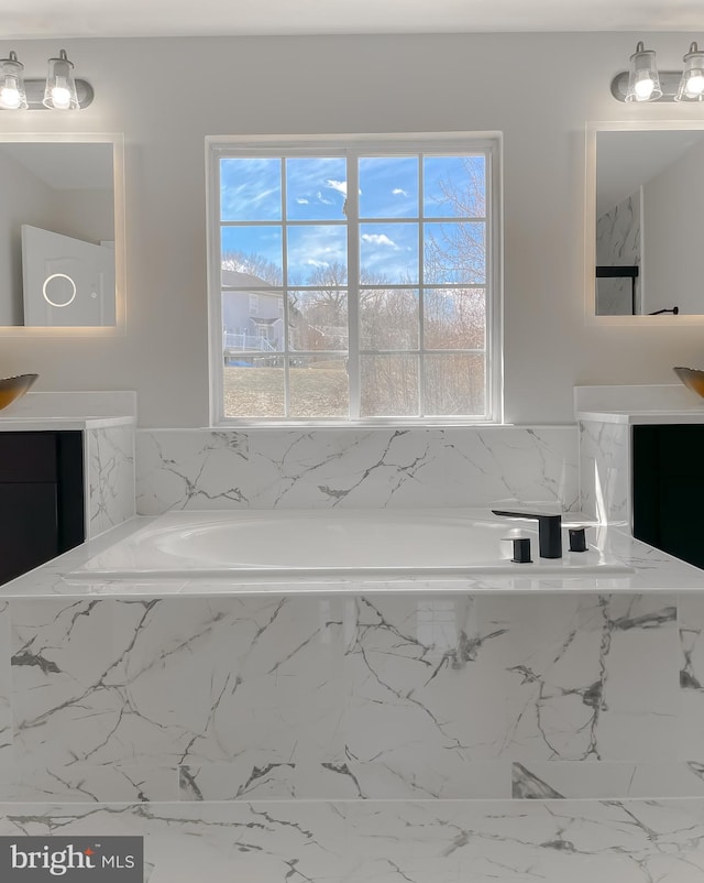 bathroom featuring a bath, a healthy amount of sunlight, and vanity