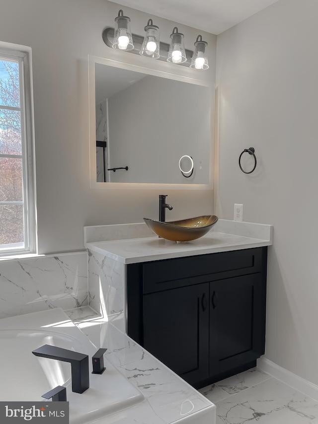 bathroom featuring plenty of natural light, marble finish floor, vanity, and baseboards