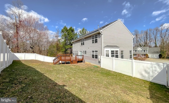 back of house featuring a fenced backyard, a lawn, and a wooden deck