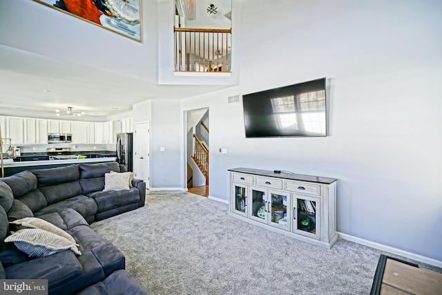 carpeted living area featuring visible vents, baseboards, and stairs