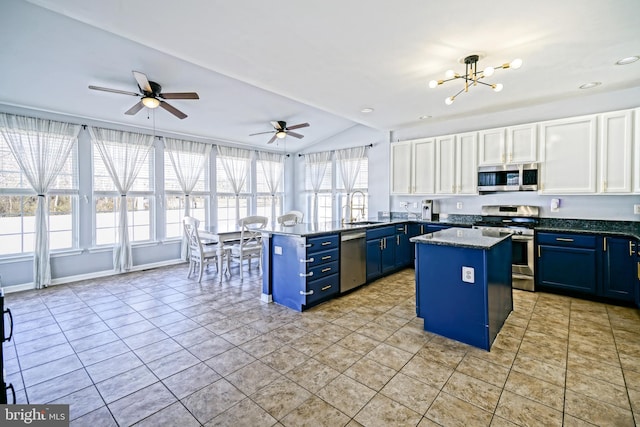 kitchen with blue cabinetry, appliances with stainless steel finishes, a peninsula, white cabinets, and a sink