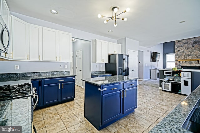 kitchen with a center island, freestanding refrigerator, a notable chandelier, white cabinets, and blue cabinets