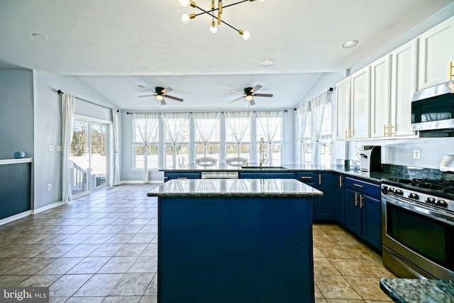 kitchen with blue cabinets, a sink, stainless steel appliances, a peninsula, and vaulted ceiling