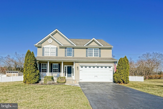 traditional home featuring driveway, fence, covered porch, a front yard, and an attached garage