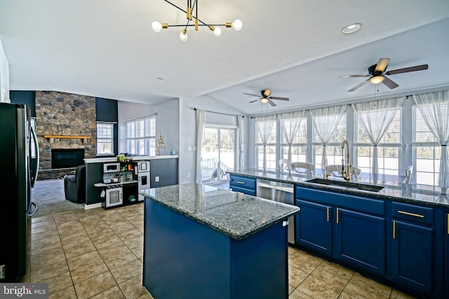 kitchen featuring blue cabinets, a sink, a kitchen island, open floor plan, and freestanding refrigerator