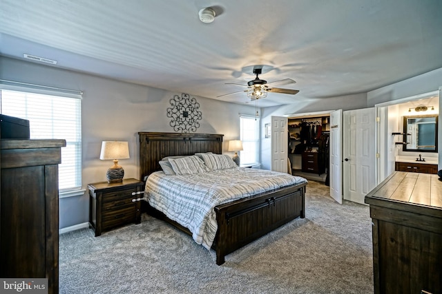 carpeted bedroom featuring visible vents, multiple windows, ensuite bath, and a walk in closet