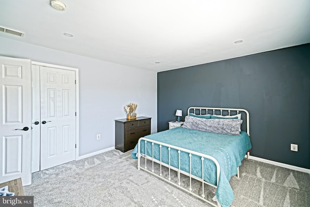 carpeted bedroom featuring a closet, visible vents, and baseboards