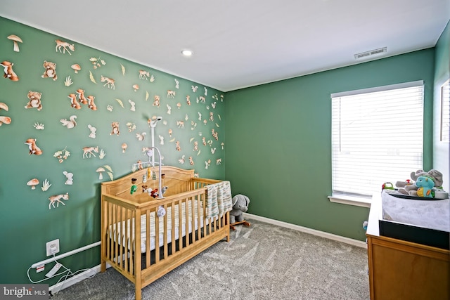 bedroom featuring visible vents, a crib, carpet, and baseboards