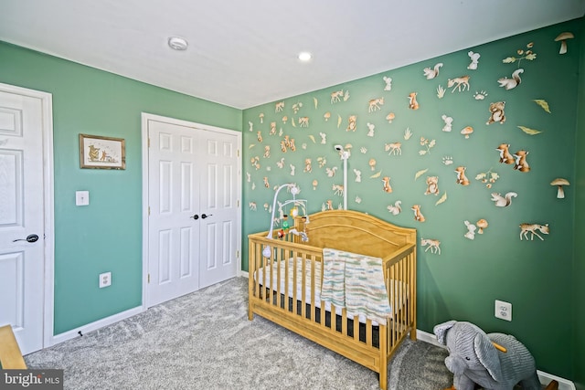 bedroom featuring a nursery area, a closet, baseboards, and carpet