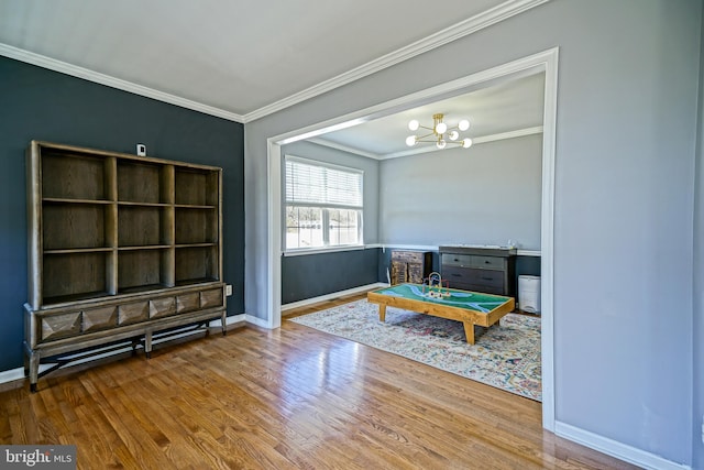 interior space featuring an inviting chandelier, crown molding, baseboards, and wood finished floors