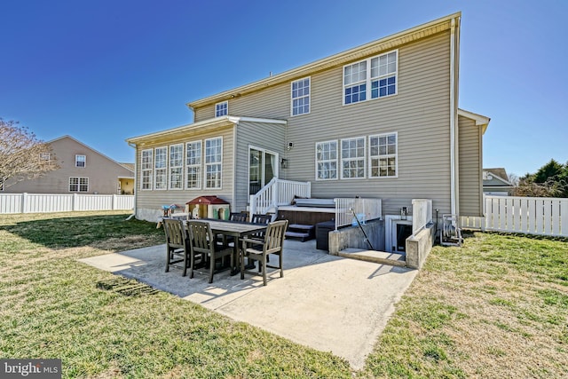 back of house featuring a patio area, a lawn, a hot tub, and fence