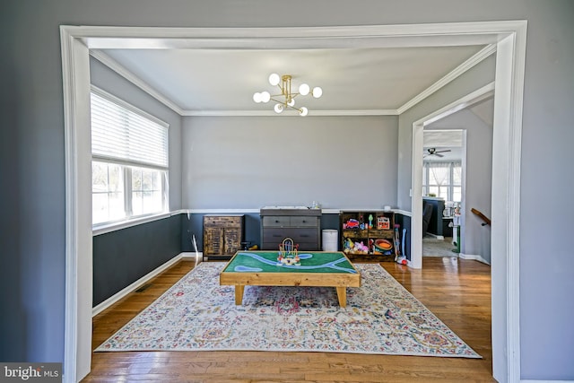 playroom with a wealth of natural light, crown molding, and wood finished floors