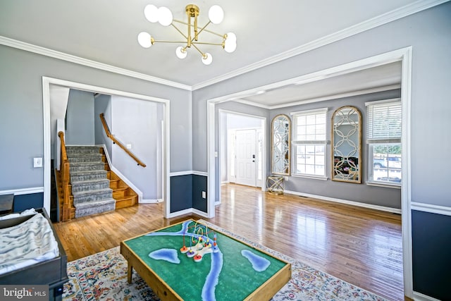 recreation room with baseboards, an inviting chandelier, wood finished floors, and ornamental molding