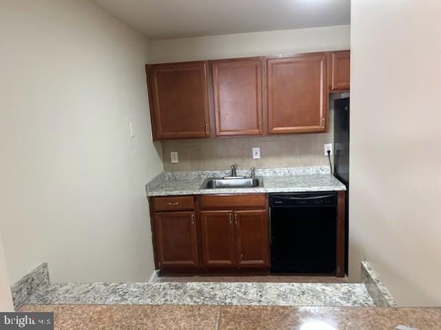 kitchen featuring decorative backsplash, light countertops, black dishwasher, and a sink