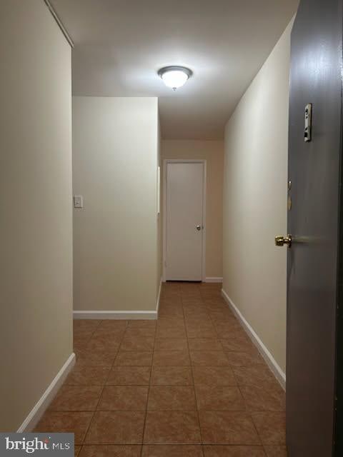 hallway featuring baseboards and light tile patterned flooring