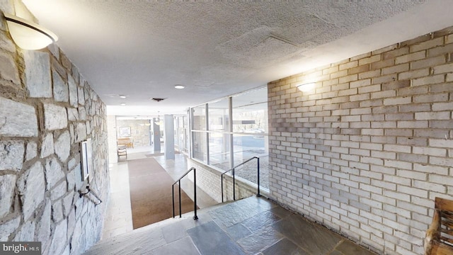 hallway with stone tile floors and a textured ceiling