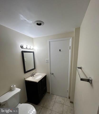 half bathroom featuring tile patterned floors, toilet, and vanity