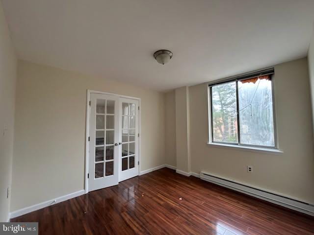 spare room with wood finished floors, french doors, baseboards, and a baseboard radiator