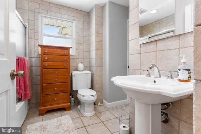 bathroom with tile patterned flooring, tile walls, and toilet