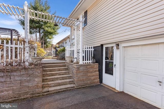 view of side of home featuring driveway, a garage, and fence