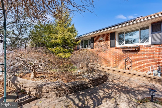 exterior space with brick siding and solar panels