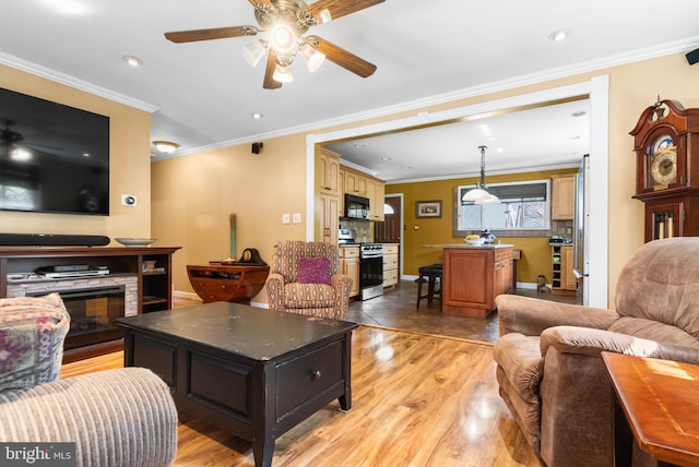 living area with light wood-style flooring, ornamental molding, a stone fireplace, baseboards, and ceiling fan