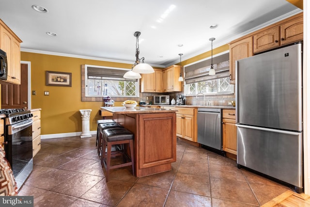 kitchen with tasteful backsplash, a kitchen island, baseboards, ornamental molding, and appliances with stainless steel finishes