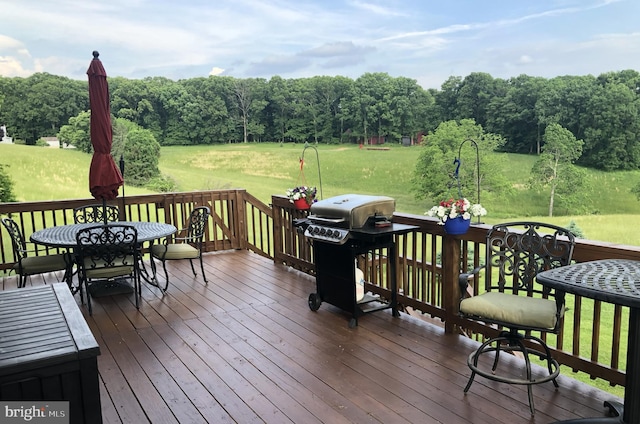 wooden deck with a yard and a grill