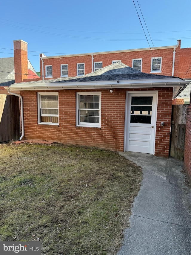 view of front of home featuring brick siding, a front yard, and fence