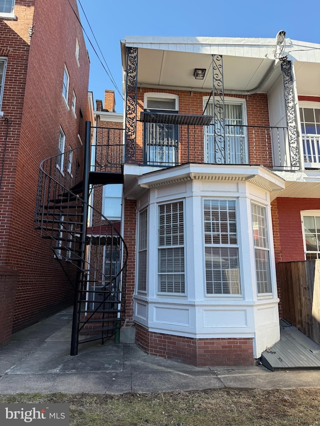 back of property featuring stairs, fence, and brick siding