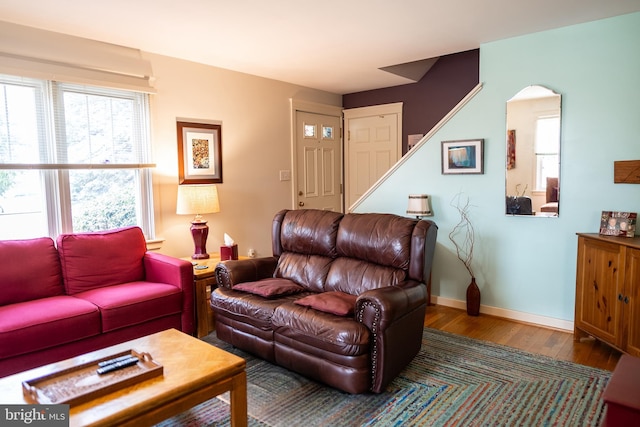 living area with stairs, wood finished floors, baseboards, and arched walkways