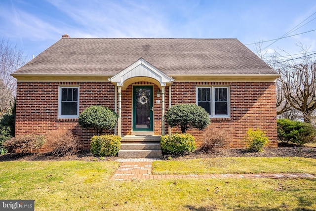 view of front facade featuring a front lawn, brick siding, and roof with shingles