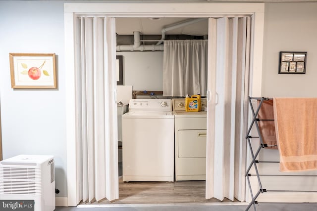 laundry room with laundry area, wood finished floors, and washer and clothes dryer