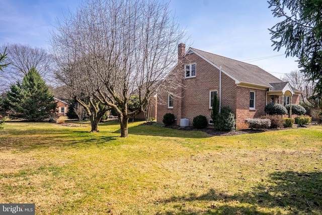 view of property exterior featuring brick siding, roof with shingles, central AC unit, a lawn, and a chimney