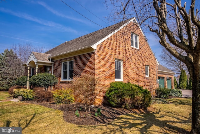 view of side of home featuring a garage, a yard, brick siding, and driveway