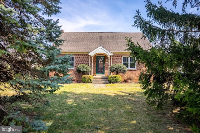 view of front of house featuring brick siding, a front lawn, and a shingled roof