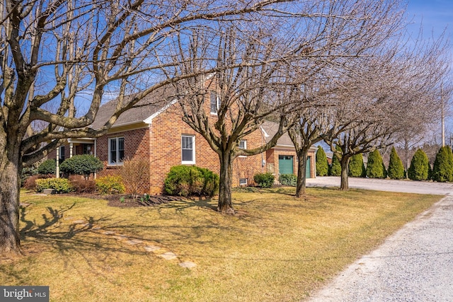 view of front of house with a front lawn, a garage, brick siding, and driveway