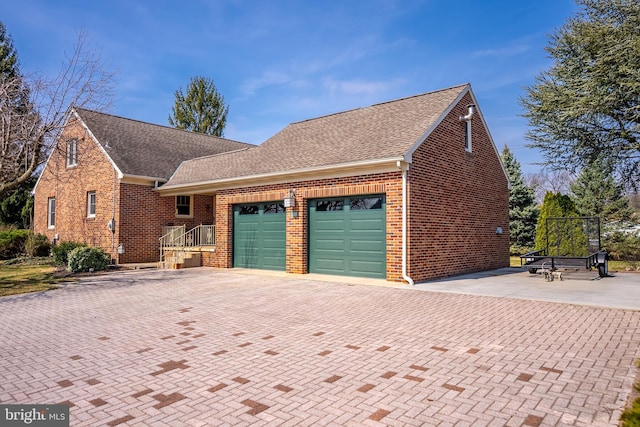 view of front of house featuring decorative driveway, brick siding, an attached garage, and a shingled roof