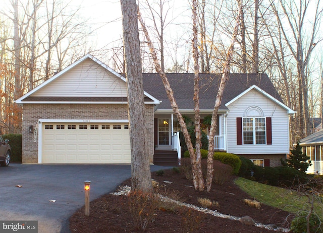 single story home featuring brick siding, driveway, an attached garage, and roof with shingles