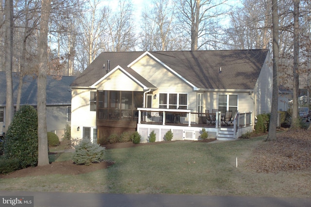 view of front of property featuring a deck, a front yard, a sunroom, and a shingled roof