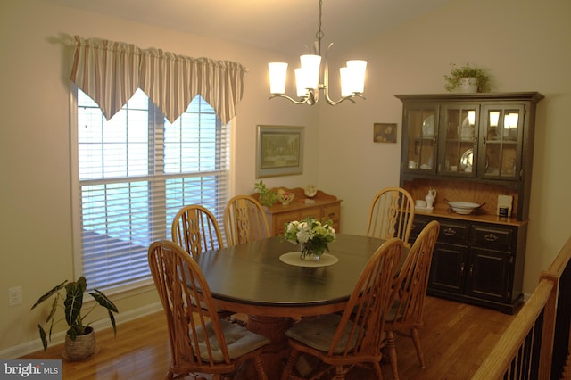 dining area with vaulted ceiling, a notable chandelier, wood finished floors, and baseboards